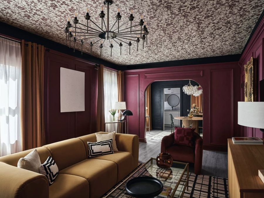 The Bordeaux Suite: a deep wine-red panelled room with a floral papered ceiling, black chandelier and a camel sofa.