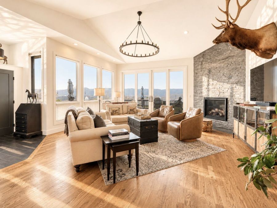 The Overlook at Monument: a vaulted great room with a stone fireplace, leather chairs and mountain views through tall windows.