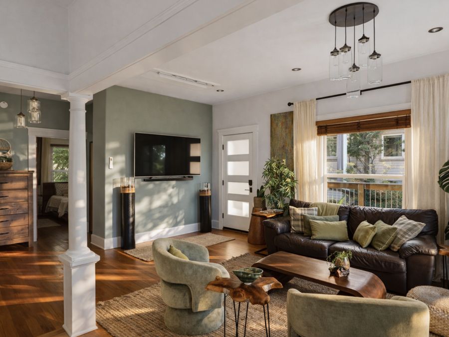 Zen Oasis: a sage-green living room with a white column, live-edge table and leather sofa.